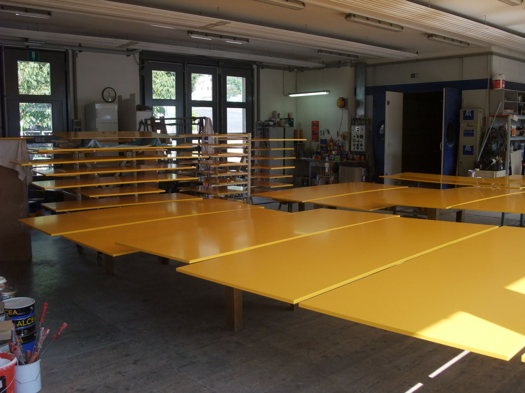 Frisch spritzlackierte gelbe MDF-Platten trocknen im Lackierraum